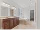 Bright bathroom featuring double vanity, soaking tub, travertine floors, and a walk-in closet at 608 East 21St St, Indianapolis, IN 46202