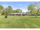 Expansive backyard featuring a lush lawn and back exterior of a home with sliding glass doors and stone facade at 6464 Whitley Ln, Indianapolis, IN 46260
