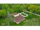 Aerial view of a home with lush landscaping, circular driveway, and detached garage at 6465 Lawrence Dr, Indianapolis, IN 46226