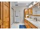 Bathroom with double sinks, wooden cabinets, walk-in shower, and a blue rug at 6465 Lawrence Dr, Indianapolis, IN 46226