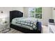 Bedroom featuring large window with black tufted headboard, side table and light floors at 7045 Gavin Dr, Indianapolis, IN 46217