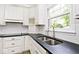 Kitchen featuring white cabinets, stainless steel sink, faucet, and a black countertop at 7245 Highburry Dr, Indianapolis, IN 46256