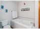 Bathroom featuring a white tiled tub, matching toilet, and tasteful wall art at 7420 Denton Cir, Indianapolis, IN 46256