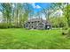 Extensive backyard with lush lawn, surrounded by trees, and outdoor seating on the patio at 7716 Traders Hollow Ln, Indianapolis, IN 46278