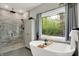 Spa-like bathroom with a soaking tub, walk-in glass shower with marble tile, and a large window with natural light at 7716 Traders Hollow Ln, Indianapolis, IN 46278