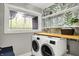 Modern laundry room equipped with a washer and dryer and a window providing a refreshing view of the outdoors at 7716 Traders Hollow Ln, Indianapolis, IN 46278