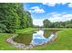 Scenic view of a serene pond surrounded by lush greenery and trees at 7716 Traders Hollow Ln, Indianapolis, IN 46278