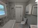 A well-lit bathroom with a toilet, vanity with sink, and a marble-tiled shower at 1009 Chestnut St, Anderson, IN 46012