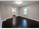 Bright living room showing dark wood floors and light gray walls, with a view of the kitchen at 1009 Chestnut St, Anderson, IN 46012