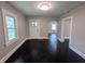 Bright living room featuring dark wood floors and light gray walls, with a view of the entryway and front door at 1009 Chestnut St, Anderson, IN 46012
