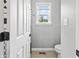 Well-lit bathroom featuring a toilet, tiled floor, and open doorway with a small window at 10504 Ruxton Ct, Fishers, IN 46040