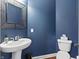 Stylish powder room with a decorative mirror, pedestal sink, and a contemporary toilet at 10504 Ruxton Ct, Fishers, IN 46040