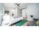 Well-lit bedroom features a ceiling fan, grey sofa, white metal bedframe, and a view to the en suite bathroom at 1112 Spann Ave, Indianapolis, IN 46203