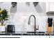 Modern kitchen featuring a stylish faucet, elegant backsplash, granite countertops, and sleek black appliances at 1112 Spann Ave, Indianapolis, IN 46203