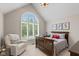 Cozy bedroom with a large window, vaulted ceilings, wooden crib, rocker and neutral color palette at 11245 Old Stone Dr, Indianapolis, IN 46236