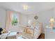Well-lit bedroom with a crib, soft colors, a window with views of the outside, and seating area at 11245 Old Stone Dr, Indianapolis, IN 46236