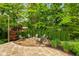 Inviting stone firepit area surrounded by Adirondack chairs, lush trees, and professional landscaping for outdoor enjoyment at 11245 Old Stone Dr, Indianapolis, IN 46236