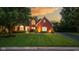 Charming brick home with a manicured lawn and beautiful landscaping, illuminated by warm exterior lighting at 11245 Old Stone Dr, Indianapolis, IN 46236