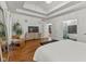 Modern bedroom with tray ceilings, hard wood floors, large TV, sitting area, and glass door entrance to the main bath at 11245 Old Stone Dr, Indianapolis, IN 46236