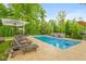 Stunning backyard pool featuring lounge chairs, umbrella, and a beautiful patio area with lush greenery and professional landscaping at 11245 Old Stone Dr, Indianapolis, IN 46236