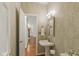 Stylish powder room with a pedestal sink, decorative wallpaper, and a doorway leading to the staircase at 11245 Old Stone Dr, Indianapolis, IN 46236
