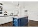 Open-concept kitchen with white cabinets, dark wood floors, and a blue island with a white countertop at 12152 Teal Ln, Carmel, IN 46032
