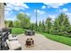 Beautiful backyard patio with outdoor seating and fire pit, surrounded by a lush lawn and mature trees at 12152 Teal Ln, Carmel, IN 46032