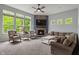 Bright living room with stone fireplace, plush seating, and large windows with wooded view at 12811 Corydon Dr, Fishers, IN 46037
