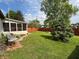 Spacious backyard featuring lush green grass, a privacy fence, a charming sunroom, and a manicured landscape at 1513 Ashley Dr, Lebanon, IN 46052