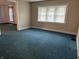 Bright room featuring teal carpet, tan walls and a multi-paned window with lace curtains at 1618 California St, Columbus, IN 47201
