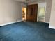 Large living room with teal carpet, tan walls, open doorways and a wooden built in at 1618 California St, Columbus, IN 47201