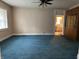 A spacious living room featuring blue carpet, a window with lace curtains, and a built-in cabinet at 1618 California St, Columbus, IN 47201