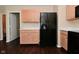 Bright kitchen showcasing a modern refrigerator and wood-look cabinets with an adjacent bathroom entrance at 1966 Freedom Ct, Greenfield, IN 46140