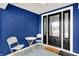 Inviting front porch with blue walls, decorated with stylish chairs, a small table, and a decorative front door at 213 S State Ave, Indianapolis, IN 46201