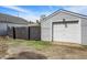 This is a detached garage with siding and a white door and dark fence adjacent to the house at 213 S State Ave, Indianapolis, IN 46201