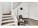 Staircase with wooden stairs and white railings, complemented by a modern floor lamp and stylish chair at 213 S State Ave, Indianapolis, IN 46201