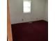 Bedroom with a single window with blinds, plus red carpet flooring and an open door at 2621 N Tacoma Ave, Indianapolis, IN 46218