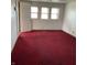 Spacious bedroom featuring three windows, red carpet flooring, and natural light at 2621 N Tacoma Ave, Indianapolis, IN 46218