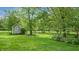 Picturesque backyard with manicured lawn, mature trees, and a charming shed, offering privacy and space at 265 Monticello Dr, Greenwood, IN 46142