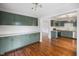 Modern kitchen with sage cabinetry, stainless steel appliances and hardwood flooring, connecting to another room at 311 Duffey St, Plainfield, IN 46168