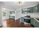 Open-concept kitchen with sage cabinets, stainless steel appliances, and plenty of natural light on wood floors at 311 Duffey St, Plainfield, IN 46168