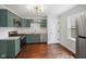 Well-lit kitchen with green cabinetry, stainless steel appliances, and hardwood floors at 311 Duffey St, Plainfield, IN 46168