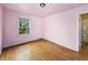 An empty bedroom features hardwood floors and one window with leafy views at 3516 Janet Dr, Indianapolis, IN 46218