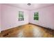 An empty bedroom features hardwood floors and two windows with leafy views at 3516 Janet Dr, Indianapolis, IN 46218