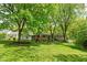 Spacious backyard featuring a swing set, lush greenery, and mature trees, perfect for outdoor activities at 5648 Rolling Ridge Rd, Indianapolis, IN 46220