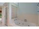 Bright bathroom featuring a large soaking tub, glass block window, and glass-enclosed shower at 5648 Rolling Ridge Rd, Indianapolis, IN 46220
