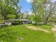 Landscaped front yard with mature trees, a lush lawn, and a flagpole adding to the property's curb appeal at 5648 Rolling Ridge Rd, Indianapolis, IN 46220