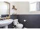 Elegant powder room featuring a pedestal sink, two-toned walls, and wood-framed mirror at 5770 Flagler Ln, Brownsburg, IN 46112