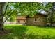 Back exterior of the home featuring a stone facade, lush lawn and back patio at 6938 Rio Grande Dr, Indianapolis, IN 46217