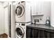 Laundry room with stacked washer and dryer and white cabinets, offering practical storage at 6938 Rio Grande Dr, Indianapolis, IN 46217